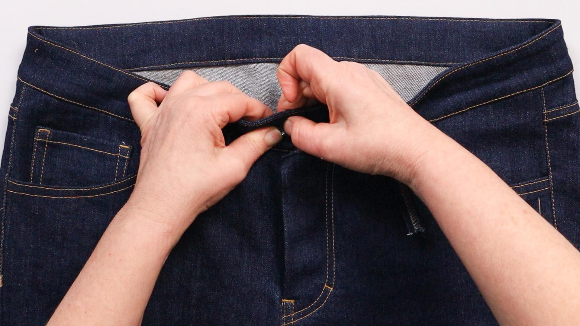 smartPATTERN Nähanleitung angesetzten Bund an Jeanshose nähen - Knopfunterteil durch geweitete Öffnung drücken