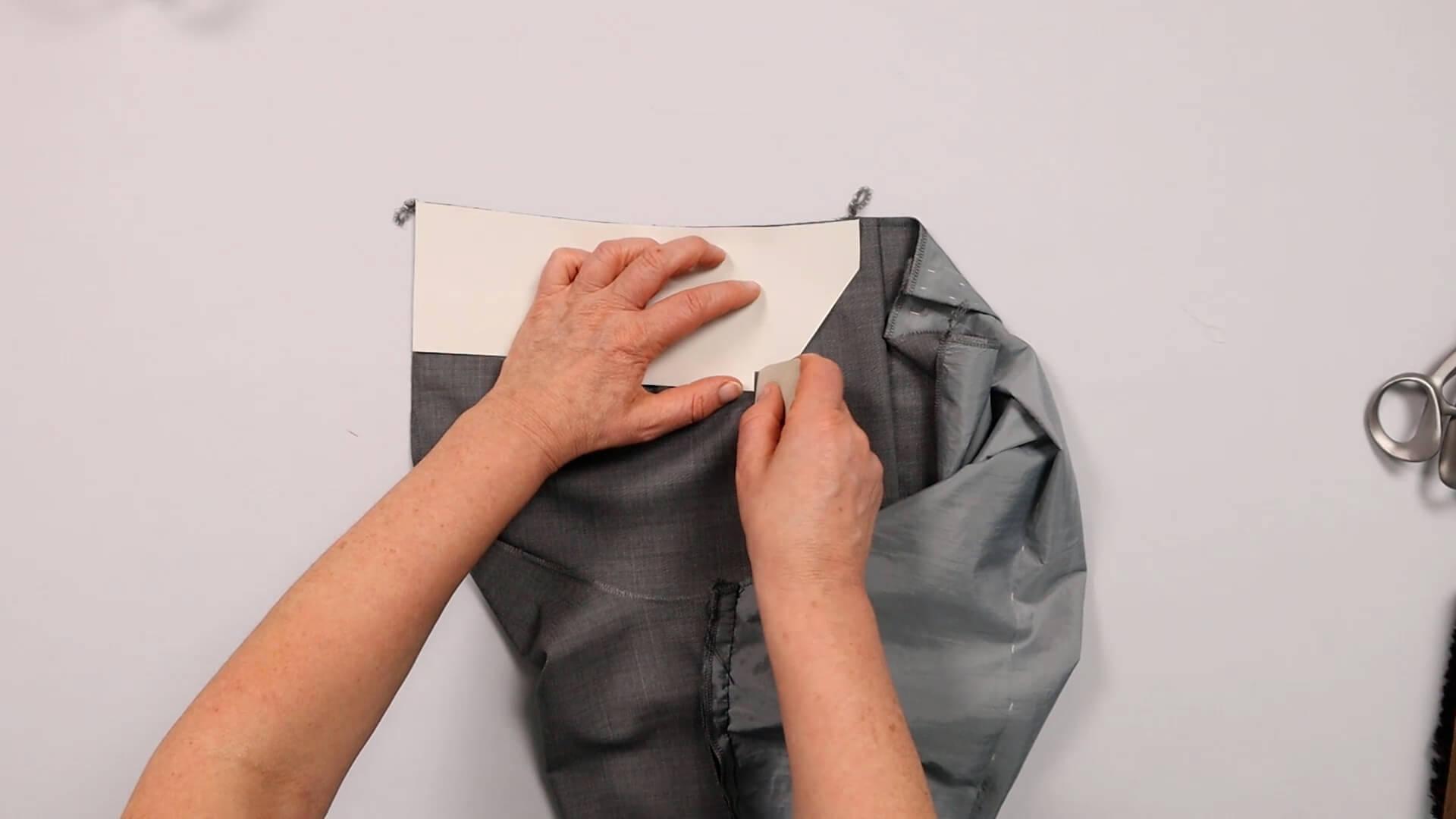 Das Bild zeigt, wie die Taschenposition für die Anprobe der Hose markiert wird.