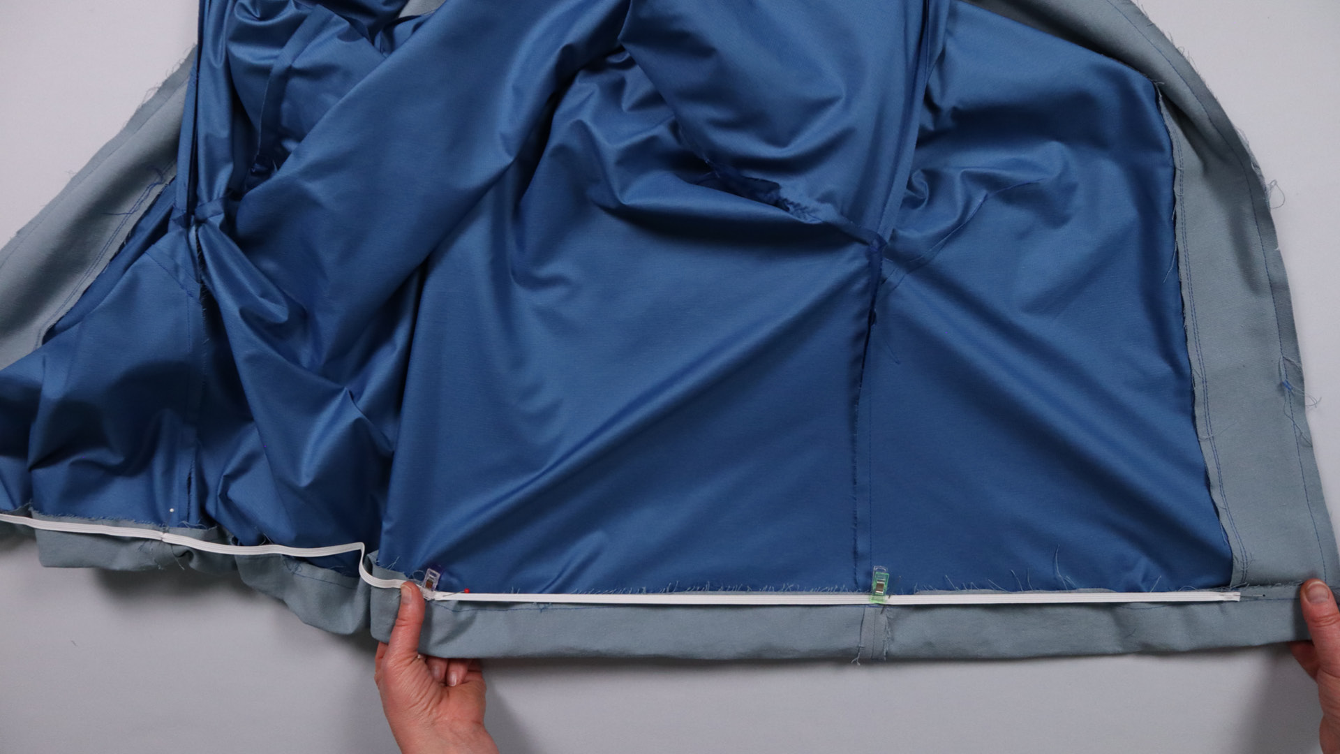 Jacke mit Kapuze nähen - Das Gummiband wird beim Annähen gezogen.